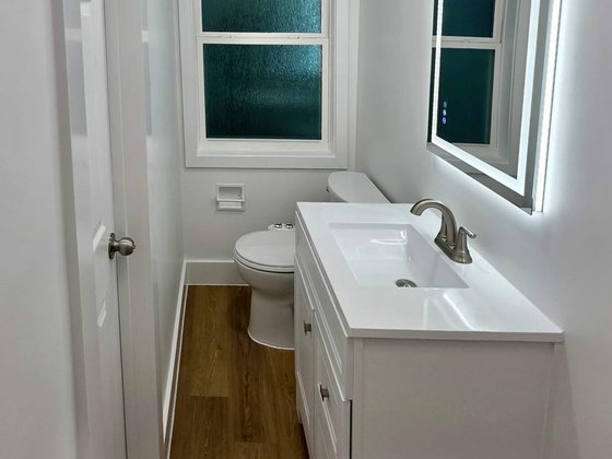 Small bathroom with a white vanity and lighted mirror