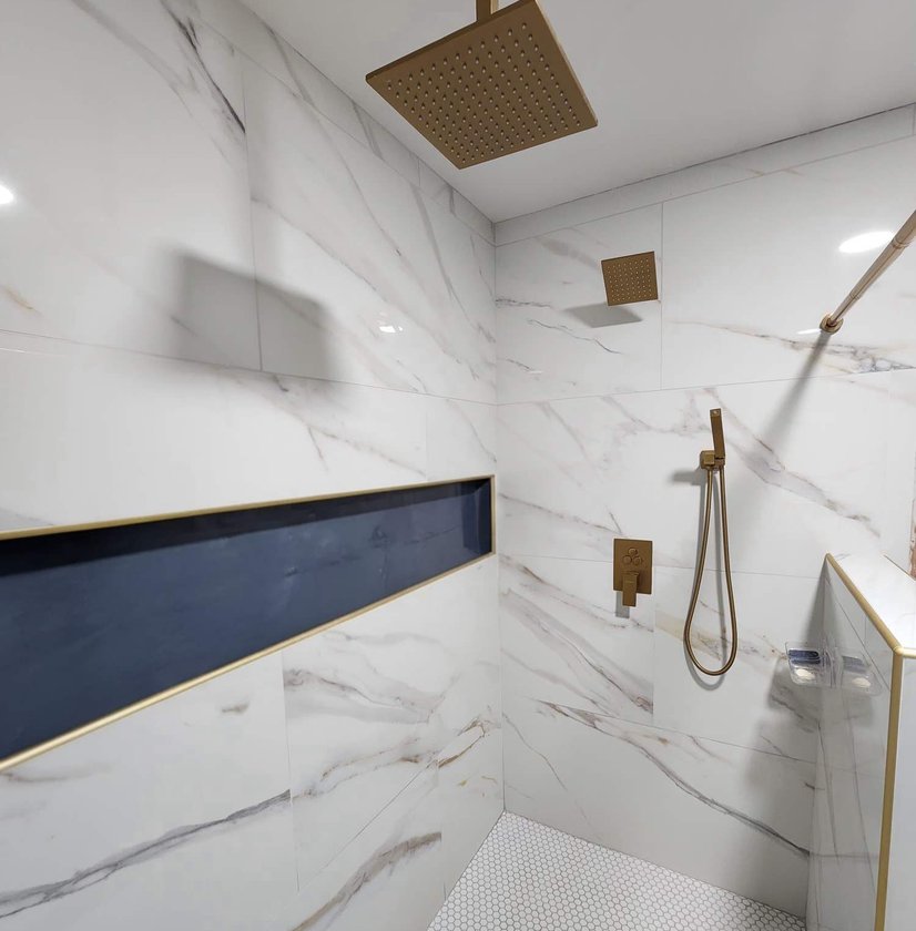 Marble-look tile shower with a navy accent niche