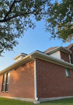 brick home with downspouts in a Houston yard