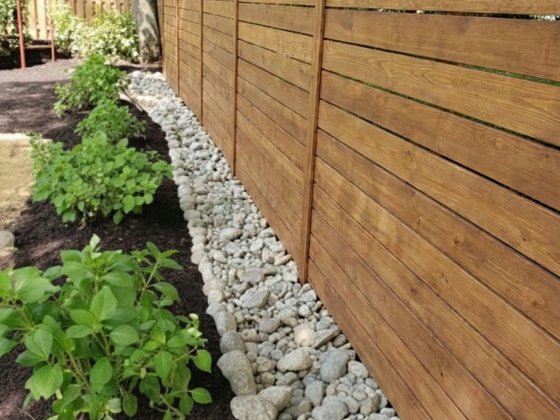 Gravel French drain along a wood fence line