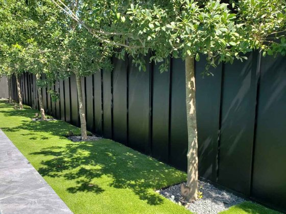 Dark horizontal board privacy fence along a backyard