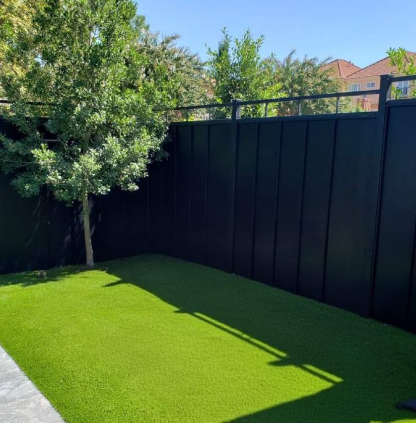 Black wood privacy fence around a backyard with artificial turf