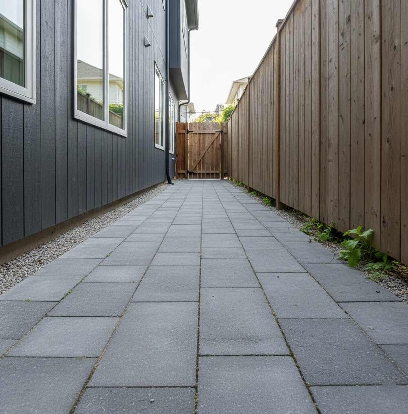Gray paver walkway along a side yard fence