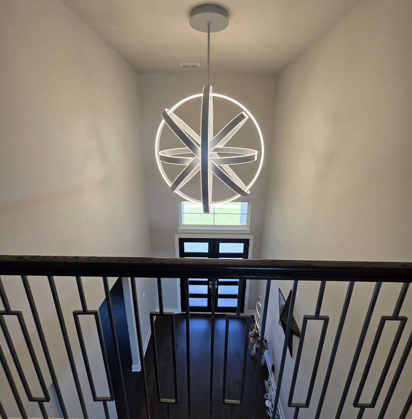 Two-story entry with a modern chandelier and iron stair railing