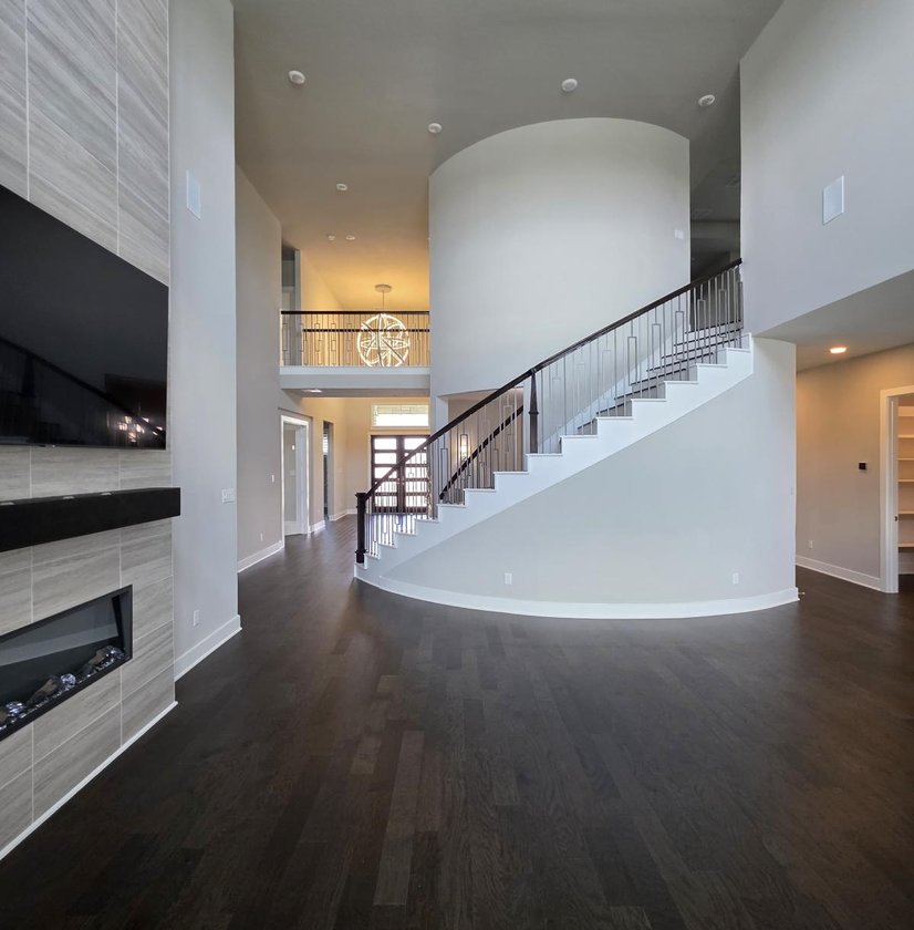 Living room with a linear fireplace and curved staircase