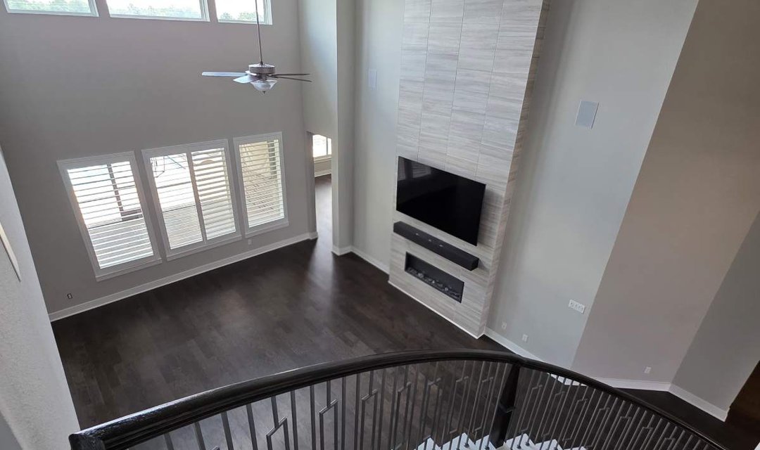 Remodeled two-story living room with a curved staircase and fireplace