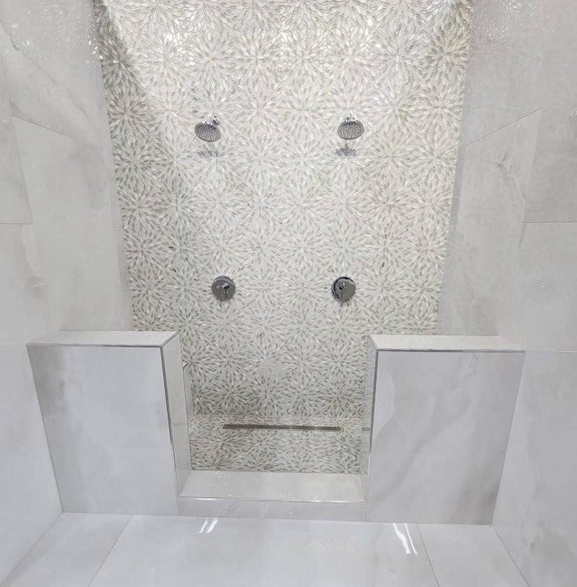 Walk-in shower with a pebble tile accent wall