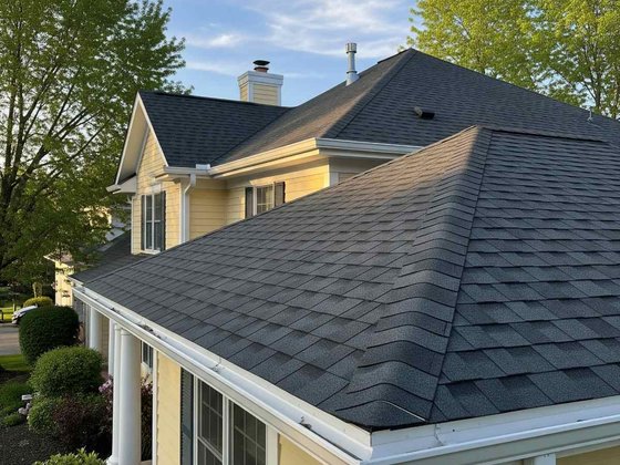 Shingle roof on a yellow house with white trim