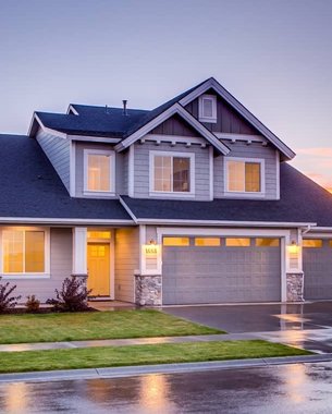 two-story house at dusk with a wet driveway after rain