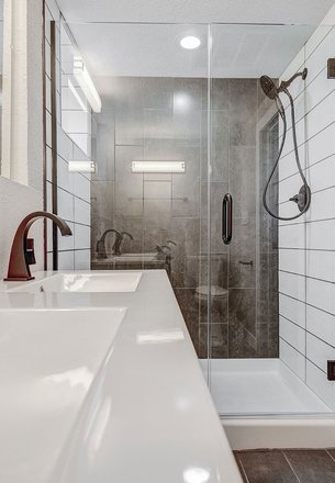 glass-enclosed walk-in shower with gray tile walls